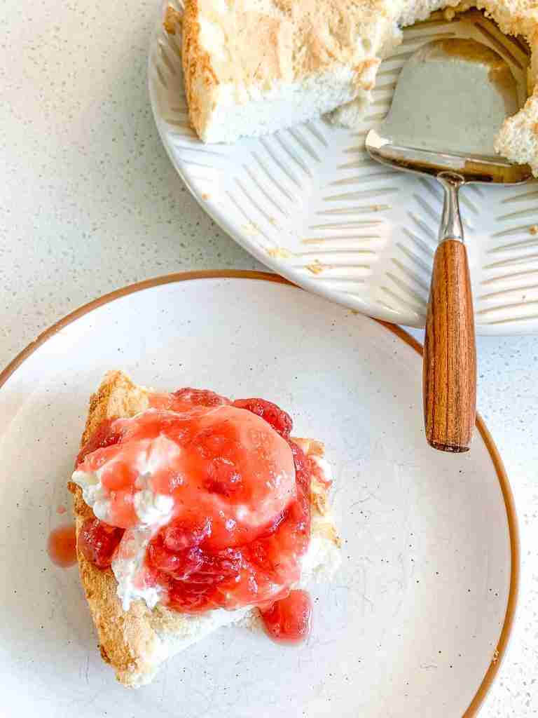 freshly baked sourdough angel food cake with a slice topped with strawberries and whipped cream