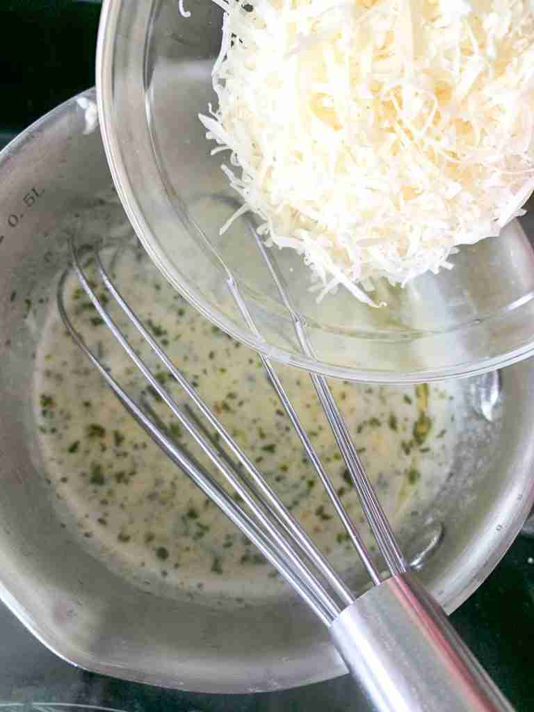 adding cheese to creamy garlic sauce