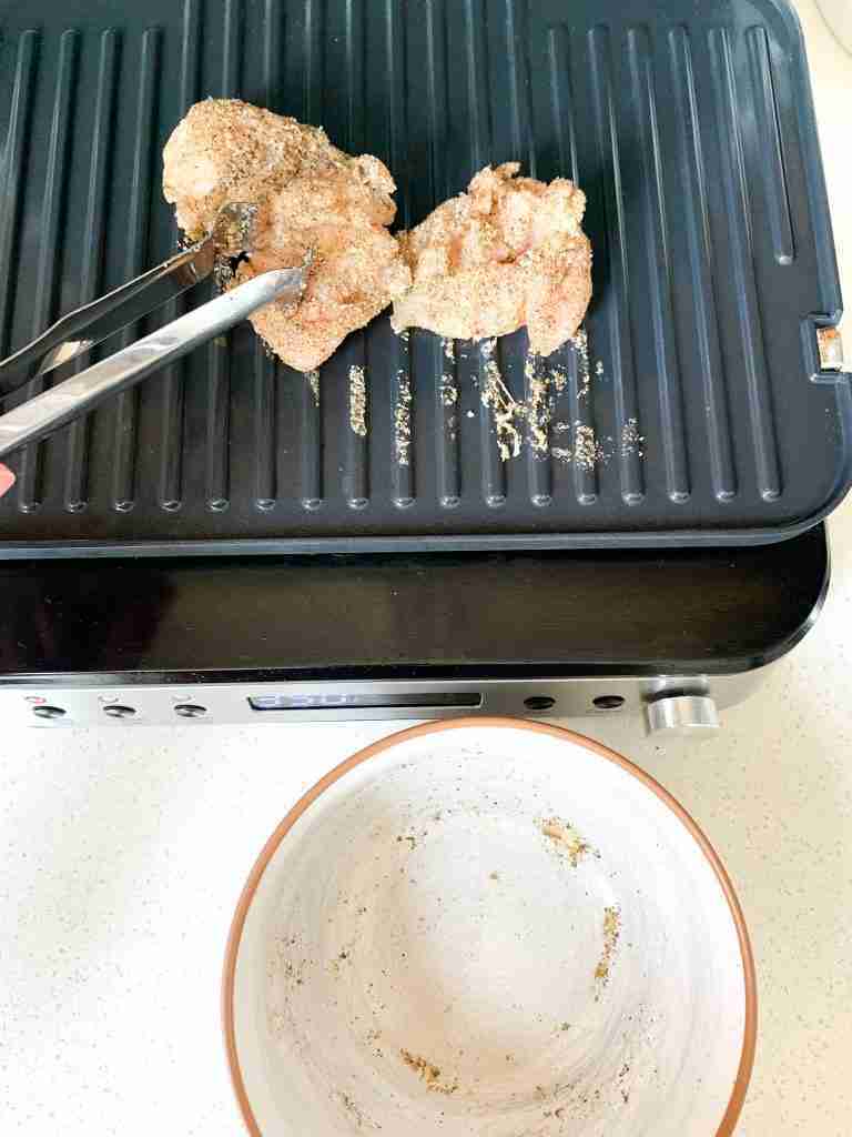 placing chicken on a grill to cook