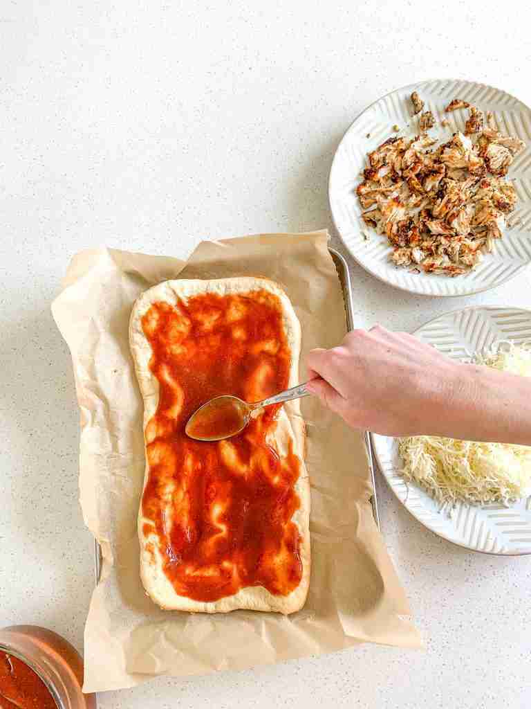 spreading bbq sauce on a flatbread
