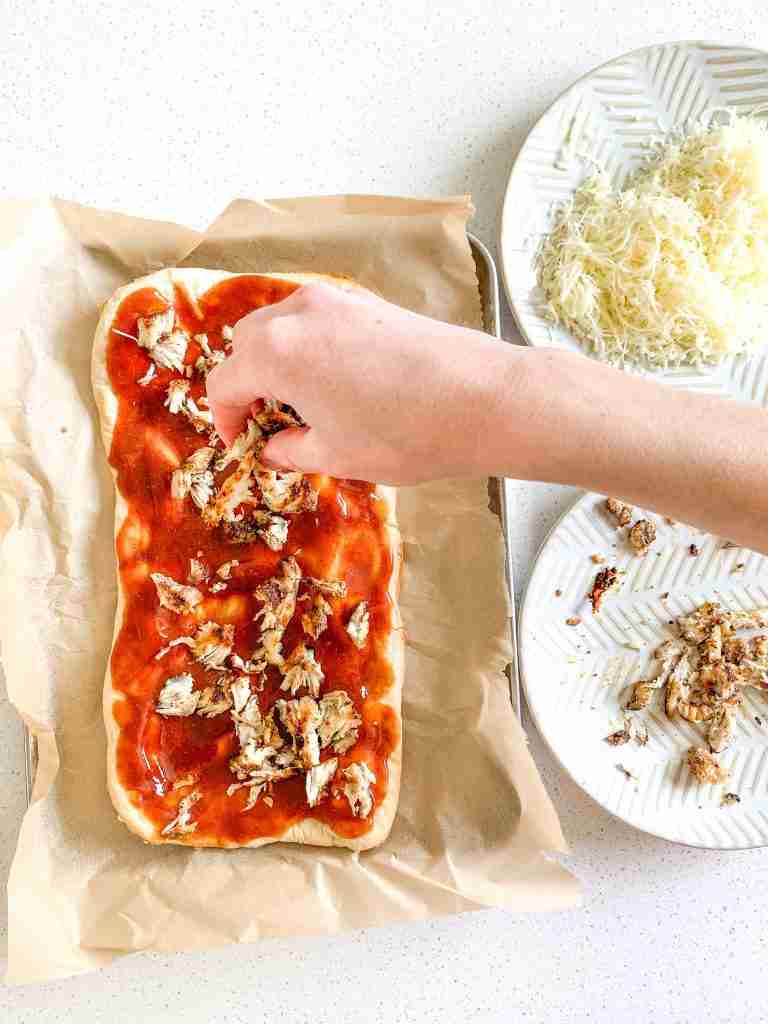 adding shredded chicken to bbq flatbread