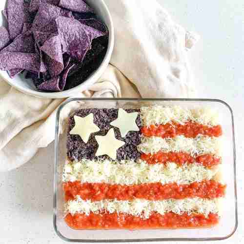 freshly made american flag taco dip with bowl of chips