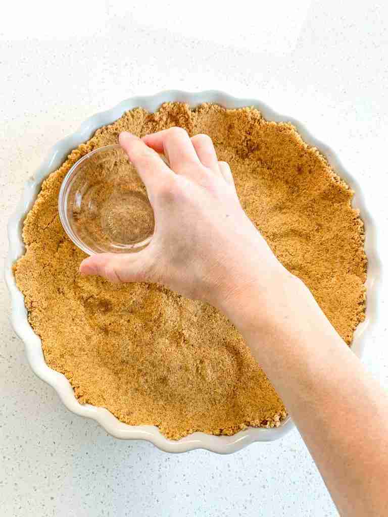 packing graham crackers down in a tart pan
