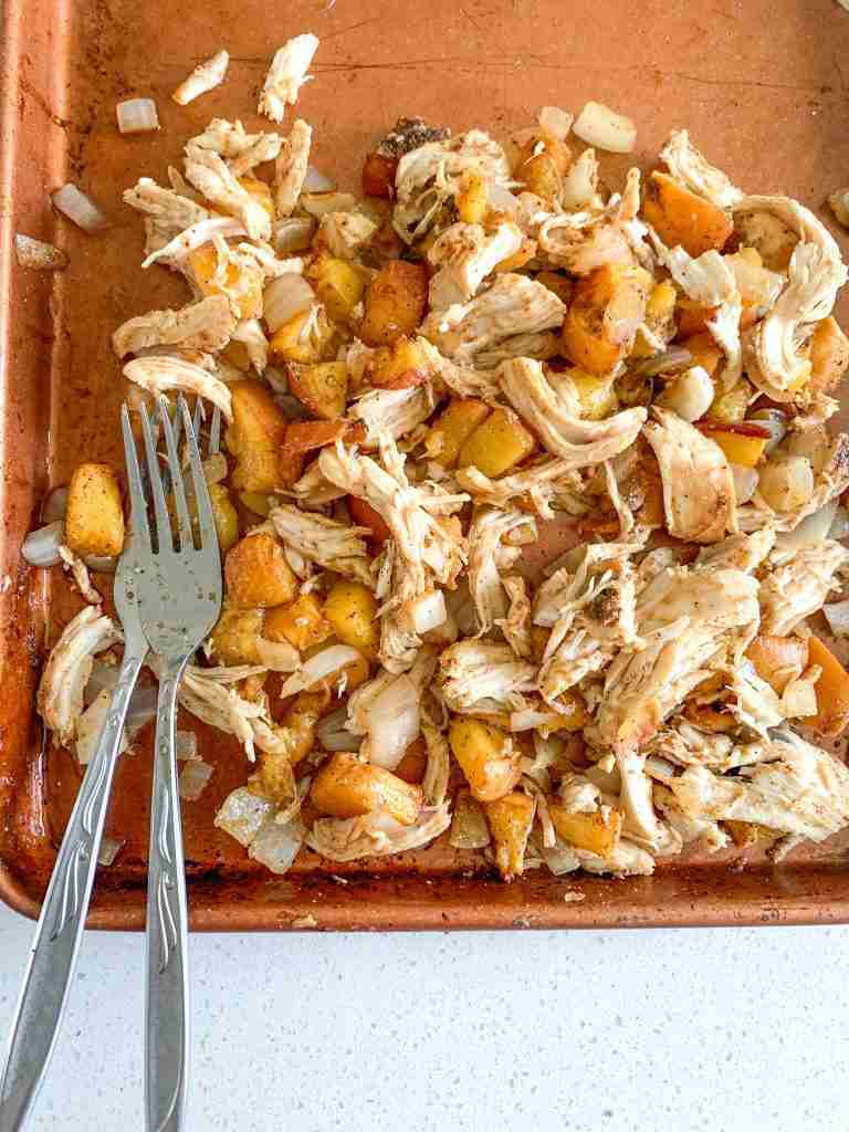shredding chicken on sheet pan after baking