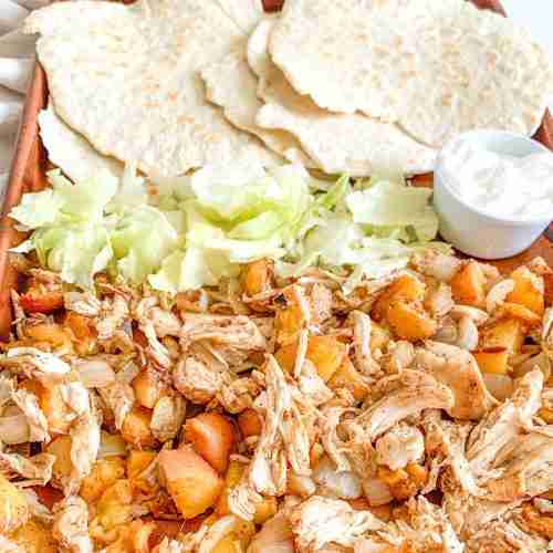 freshly cooked chipotle chicken peach tacos on a sheet pan with tortillas and fixings