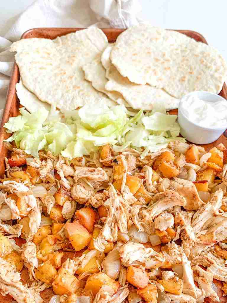 freshly cooked chipotle chicken peach tacos on a sheet pan with tortillas and fixings