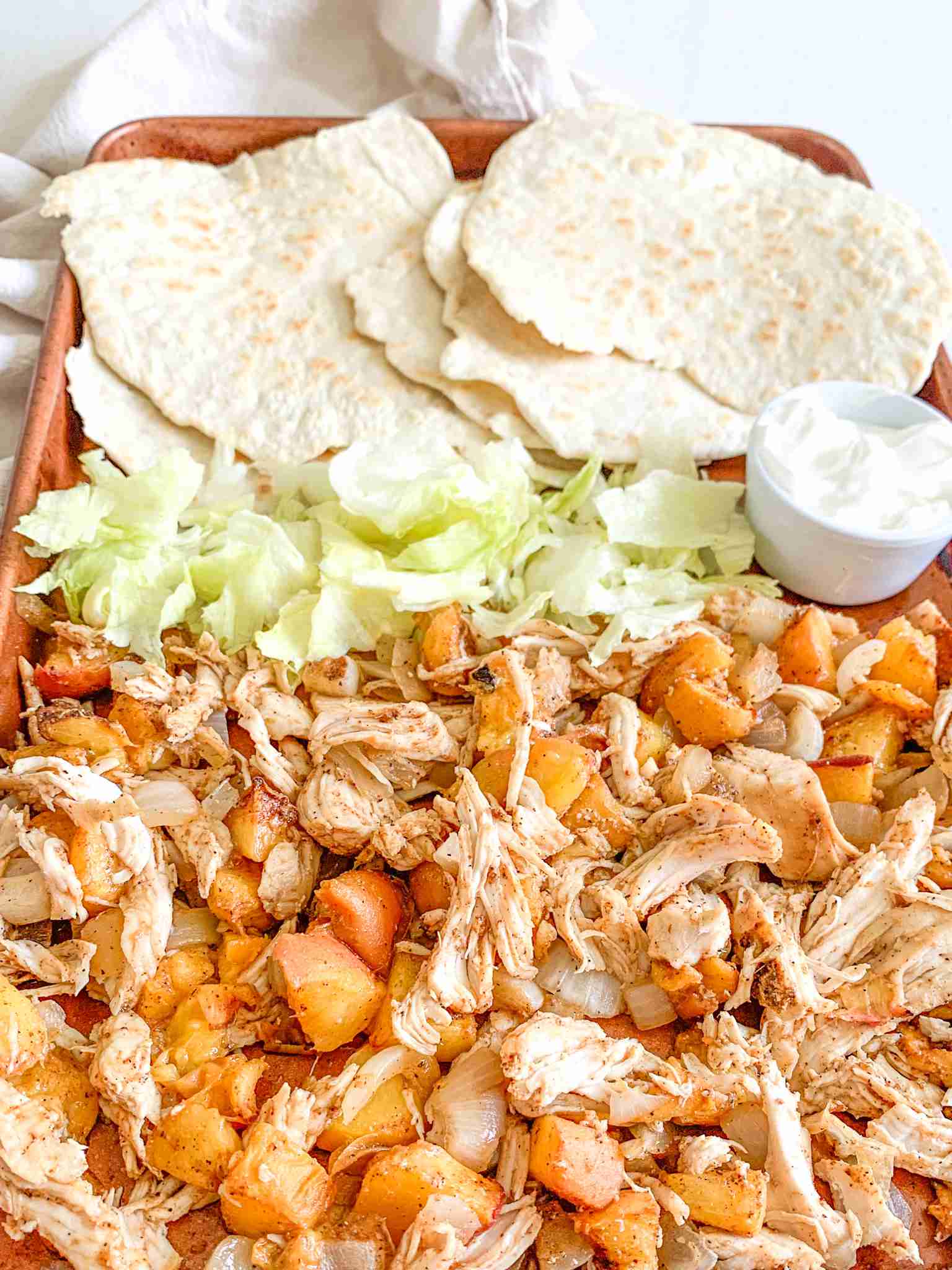 freshly cooked chipotle chicken peach tacos on a sheet pan with tortillas and fixings