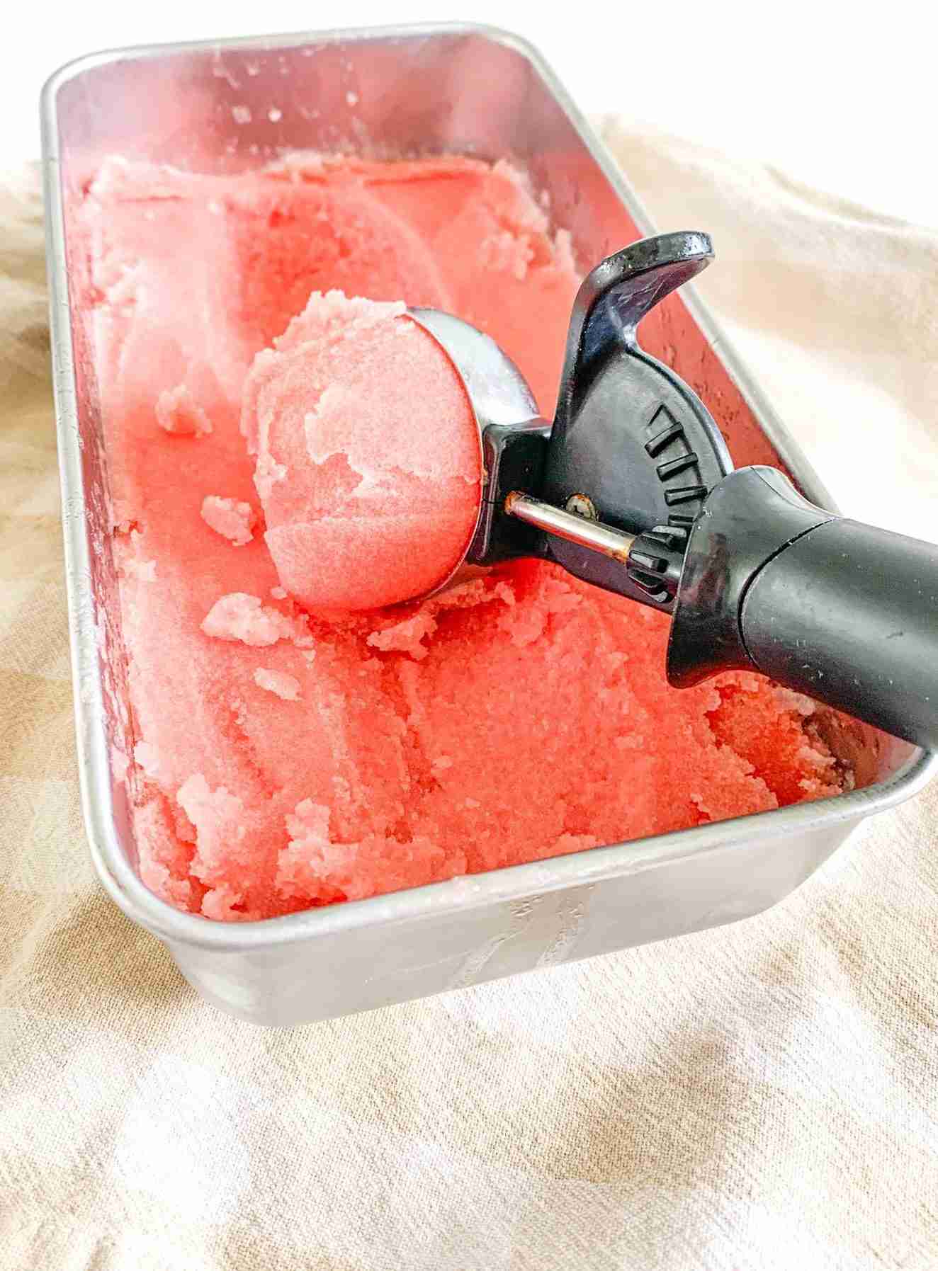 watermelon sorbet in a pan with an ice cream scooper