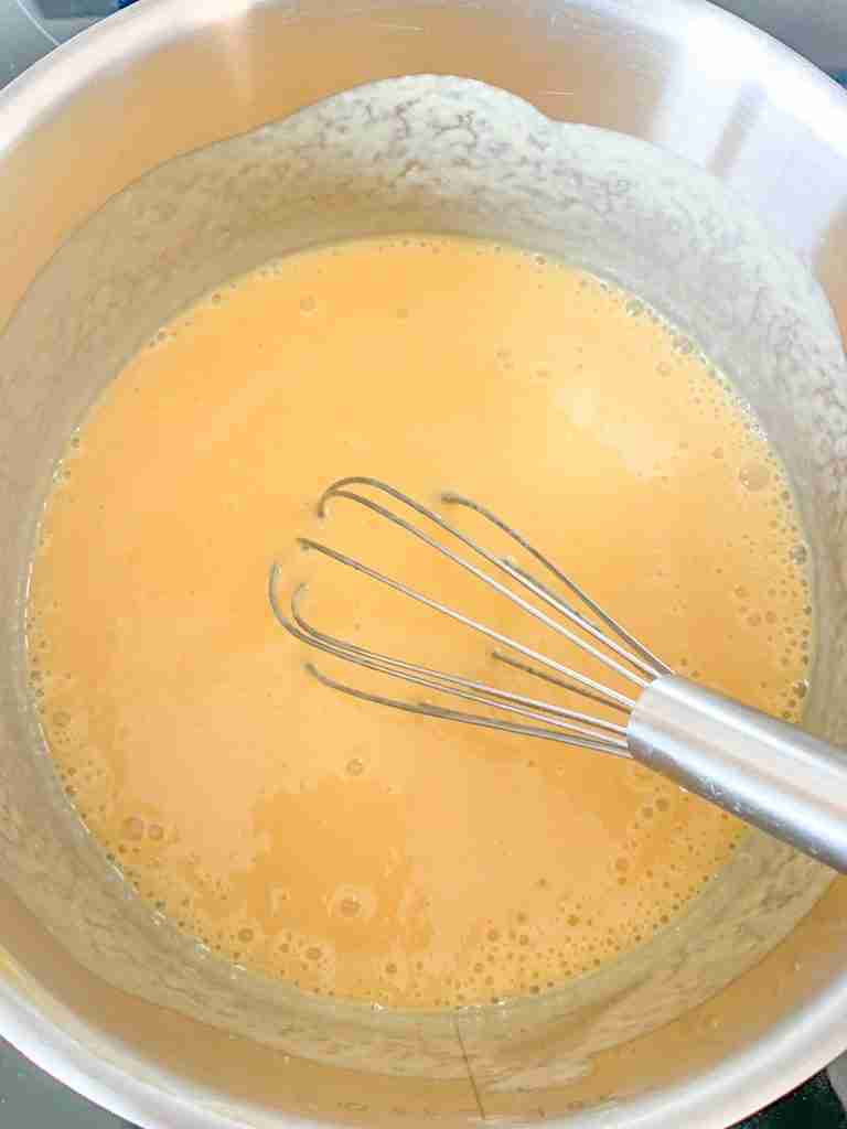 whisking peach curd on the stove