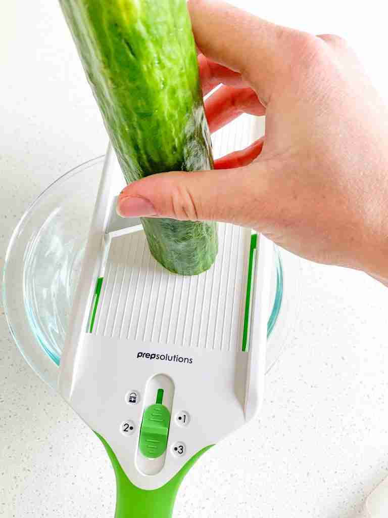 cutting a cucumber on mandolin slicer