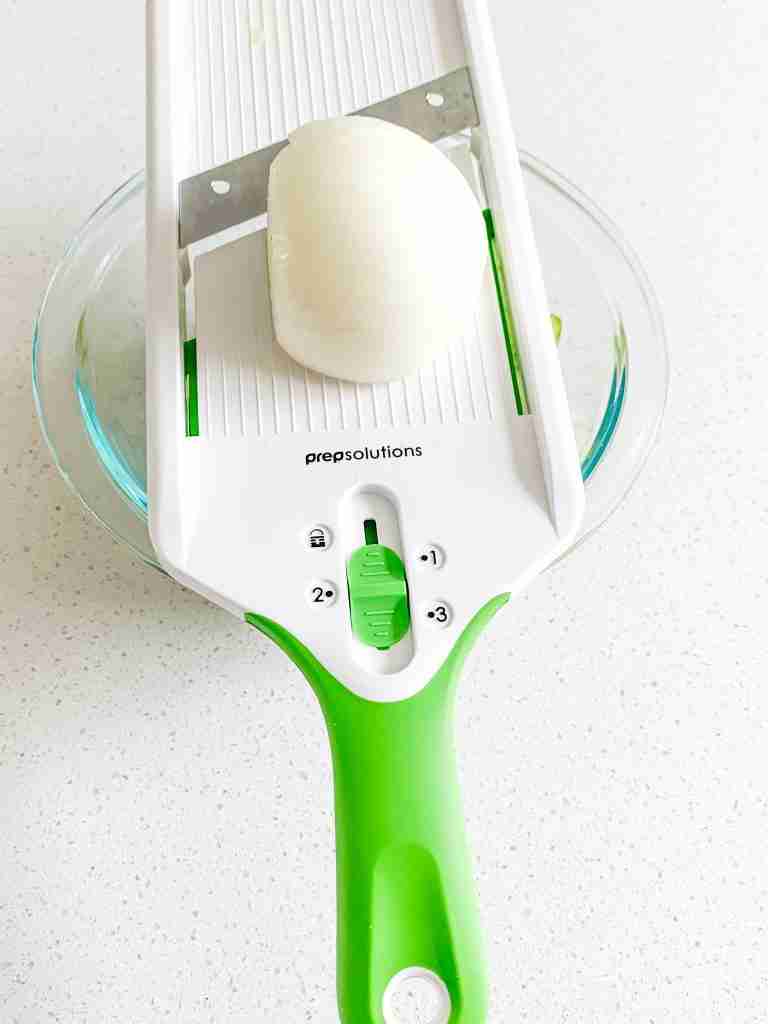 cutting a onion on mandolin slicer