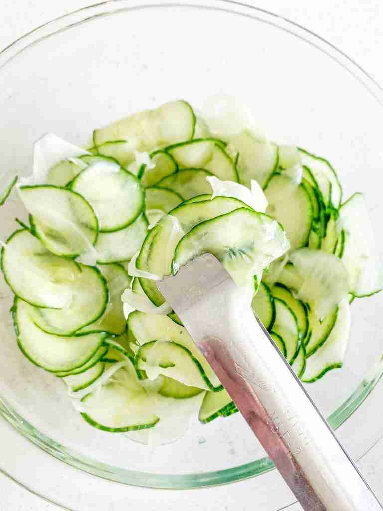 freshly made old fashioned cucumber and onion salad in tongs