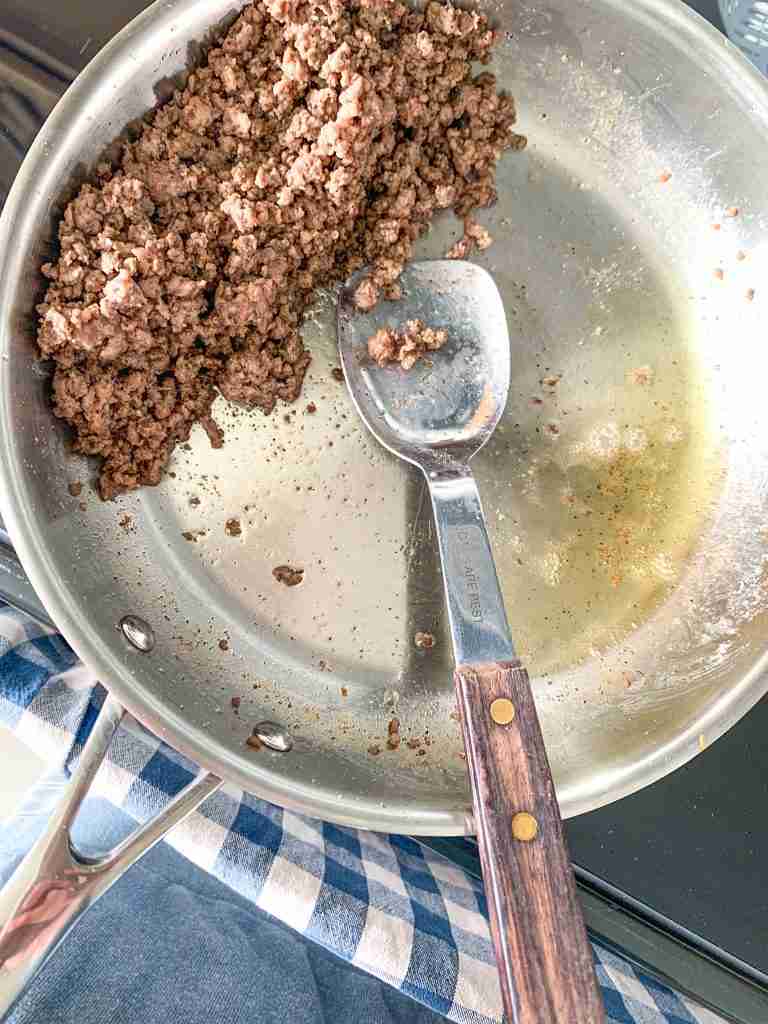 separating cooked beef from grease in a pan