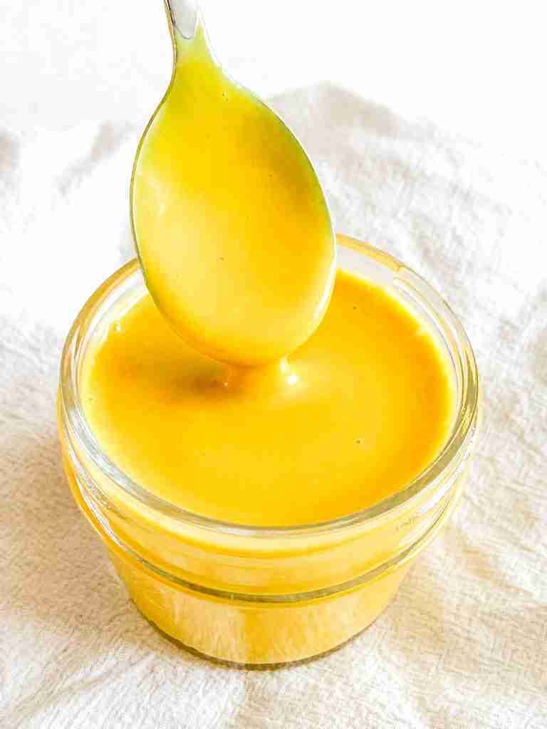 freshly made homemade honey mustard in a small jar with a spoon pulling some out