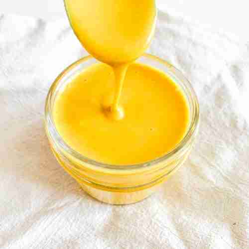 freshly made homemade honey mustard in a small jar with a spoon pulling some out