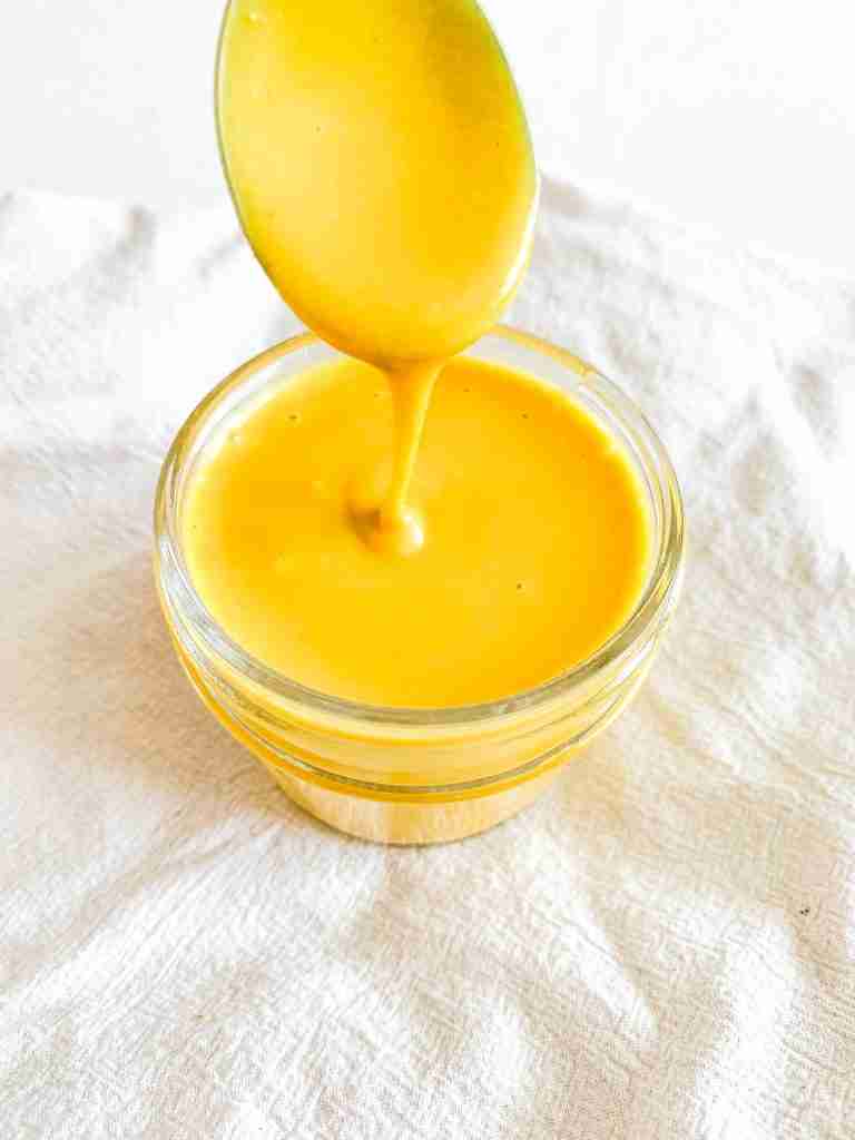 freshly made homemade honey mustard in a small jar with a spoon pulling some out