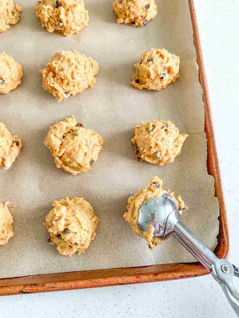 scooping sourdough pumpkin cookie dough on to a sheet pan