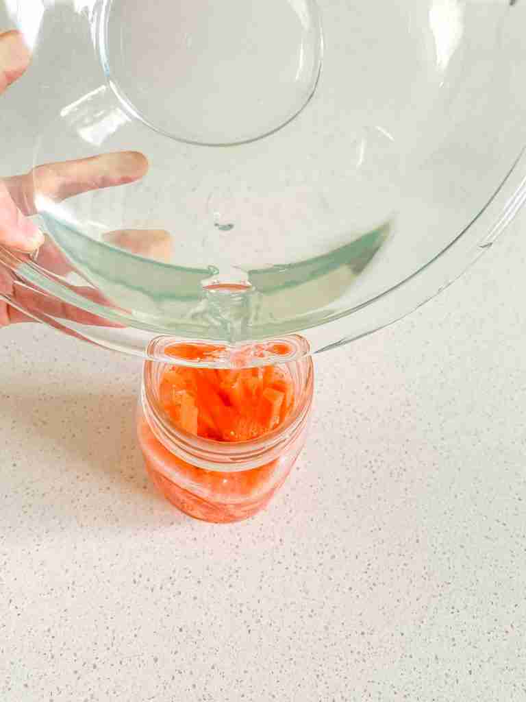 adding pickling solution into jar of carrots