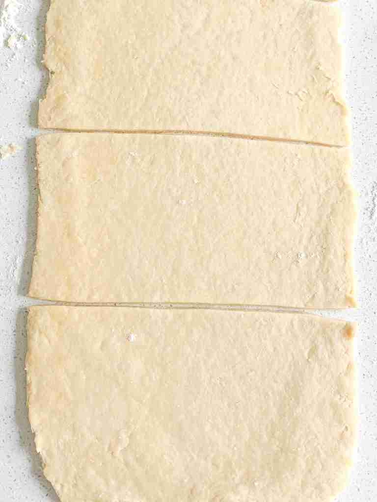 slicing turnover puff pastry dough into 3 sections