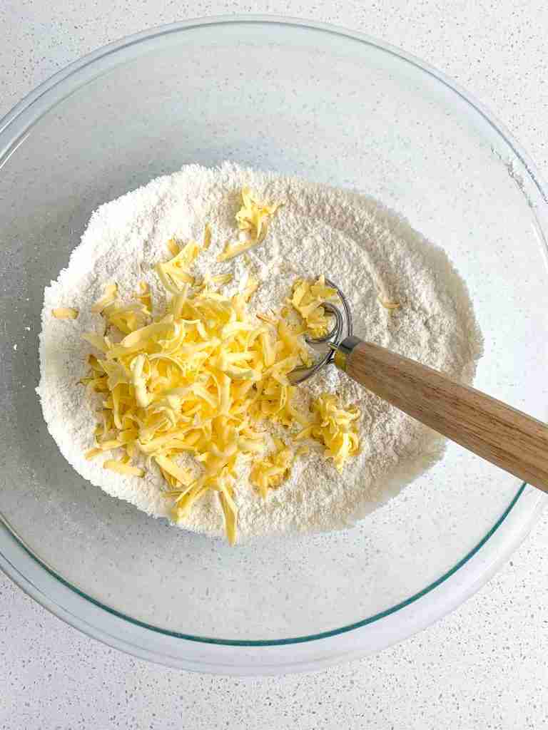 adding butter into dry mixture for biscuits