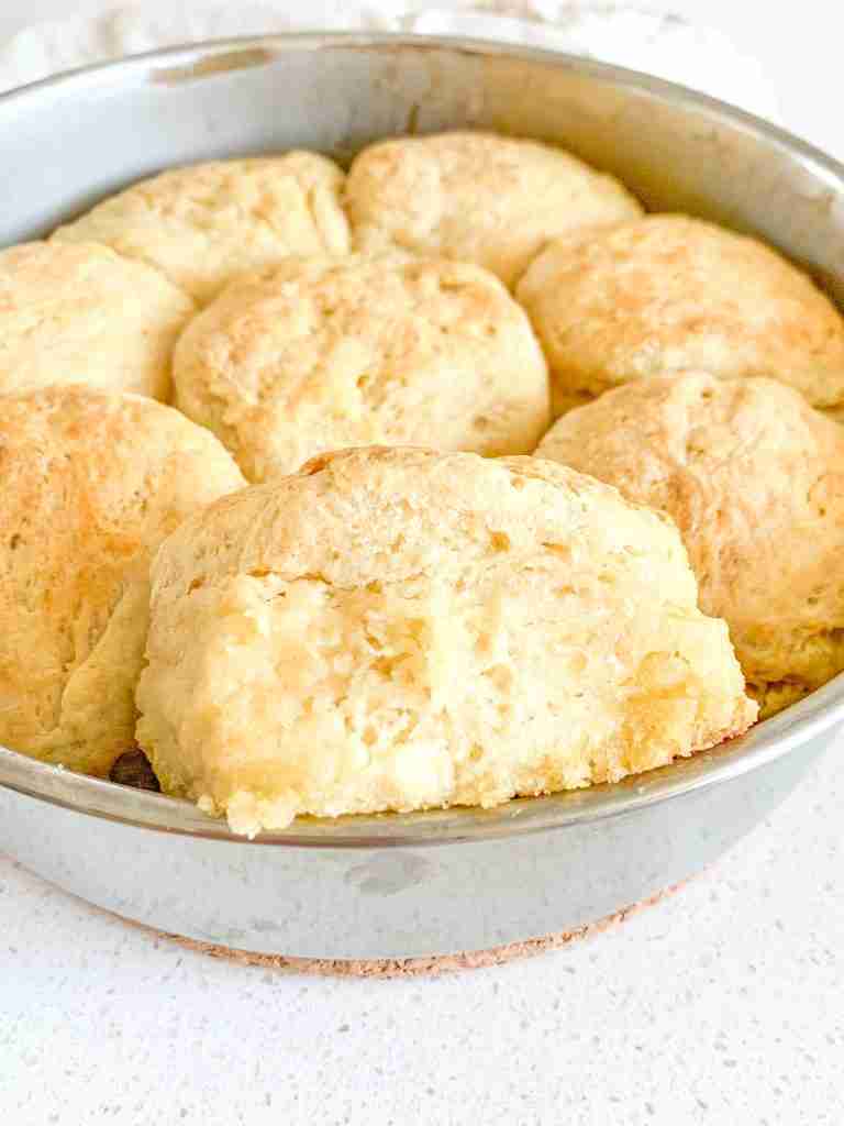 freshly baked sourdough angel biscuits with one coming out of the pan