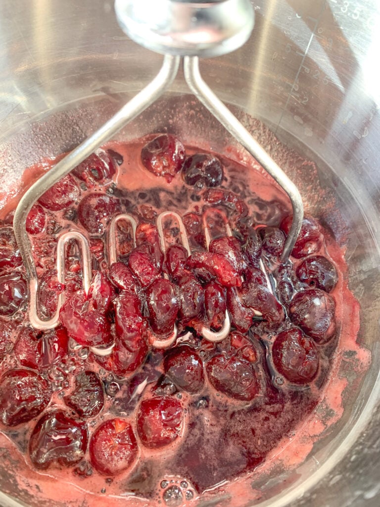 mashing cherries while making cherry filling