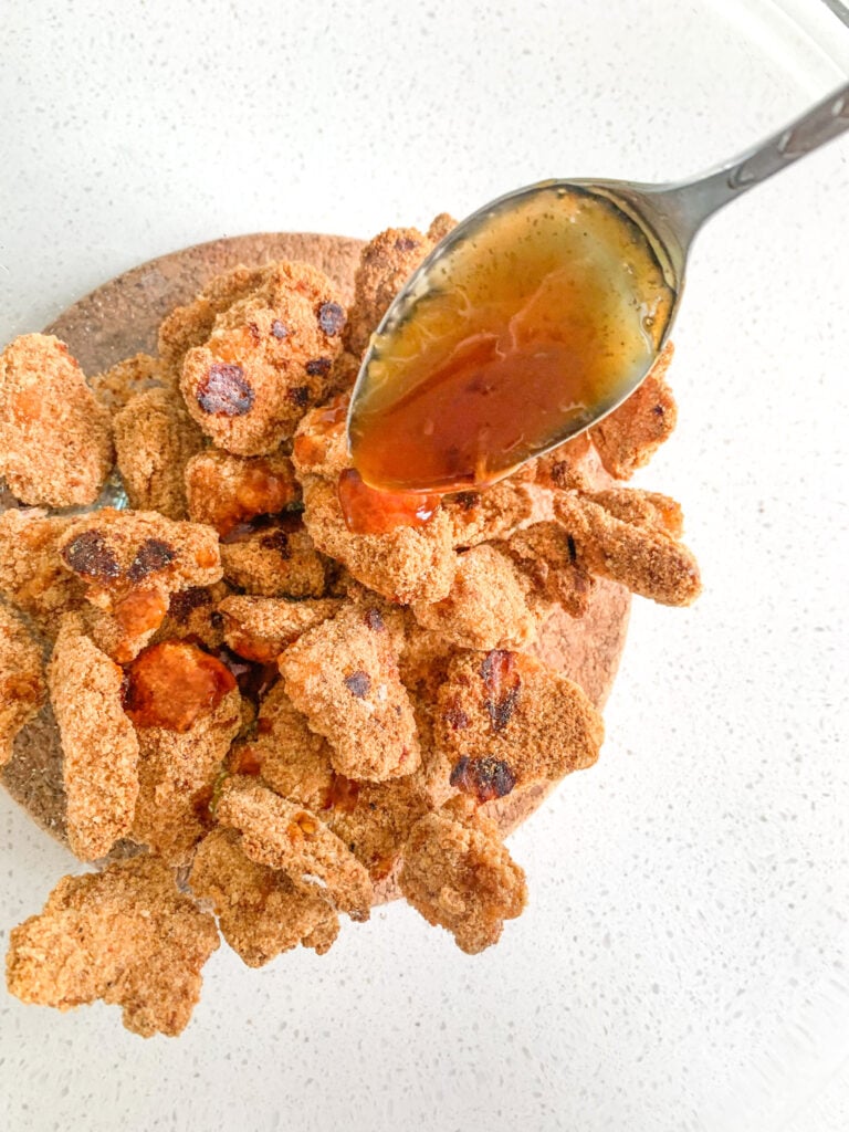 adding sauce to baked chicken