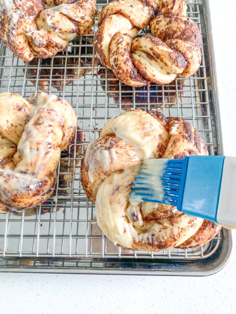 brushing baked king cakes with buttercream glaze