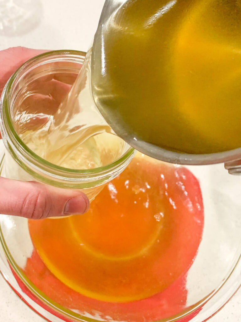 pouring chicken stock into jars
