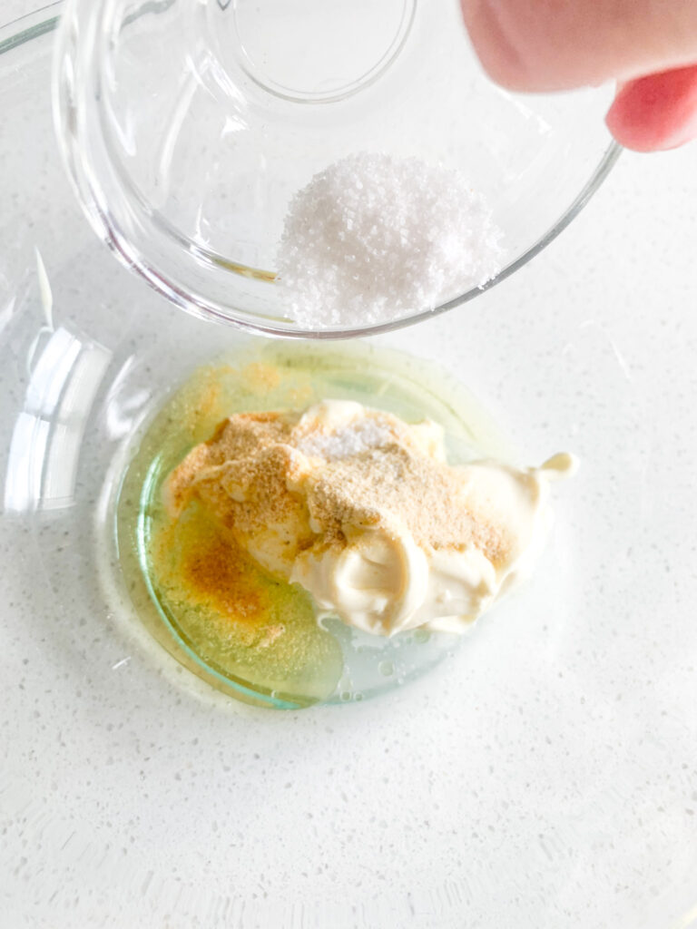adding homemade italian dressing ingredients to bowl