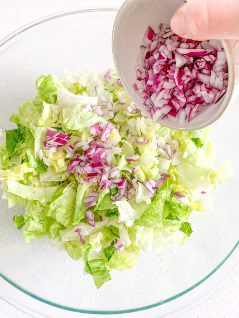 adding diced red onion to salad bowl