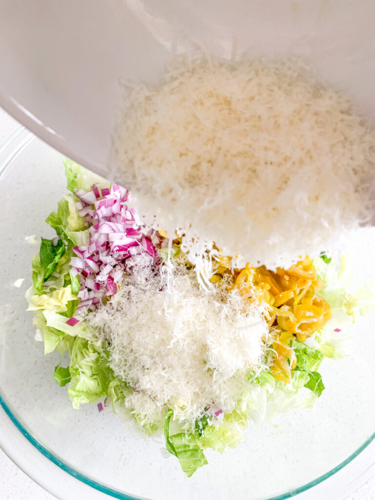 adding parmesan cheese to salad bowl