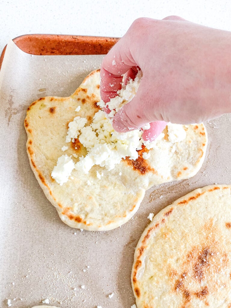 adding feta cheese to naan bread