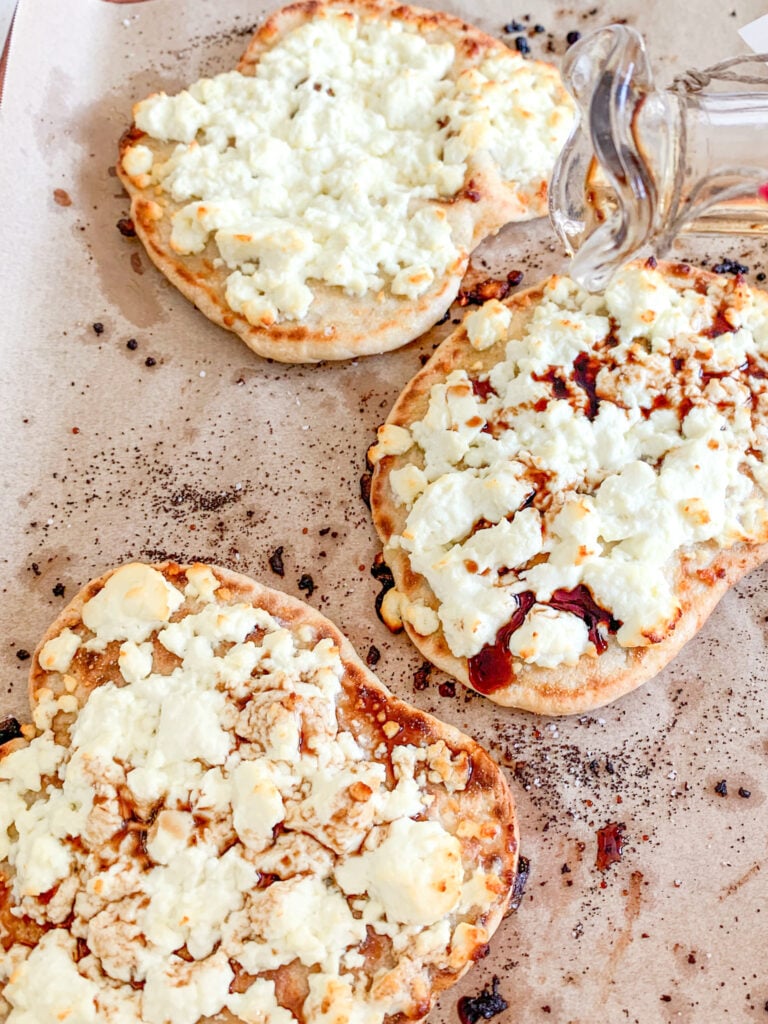 freshly baked feta naan pizza getting drizzled with balsamic vinegar