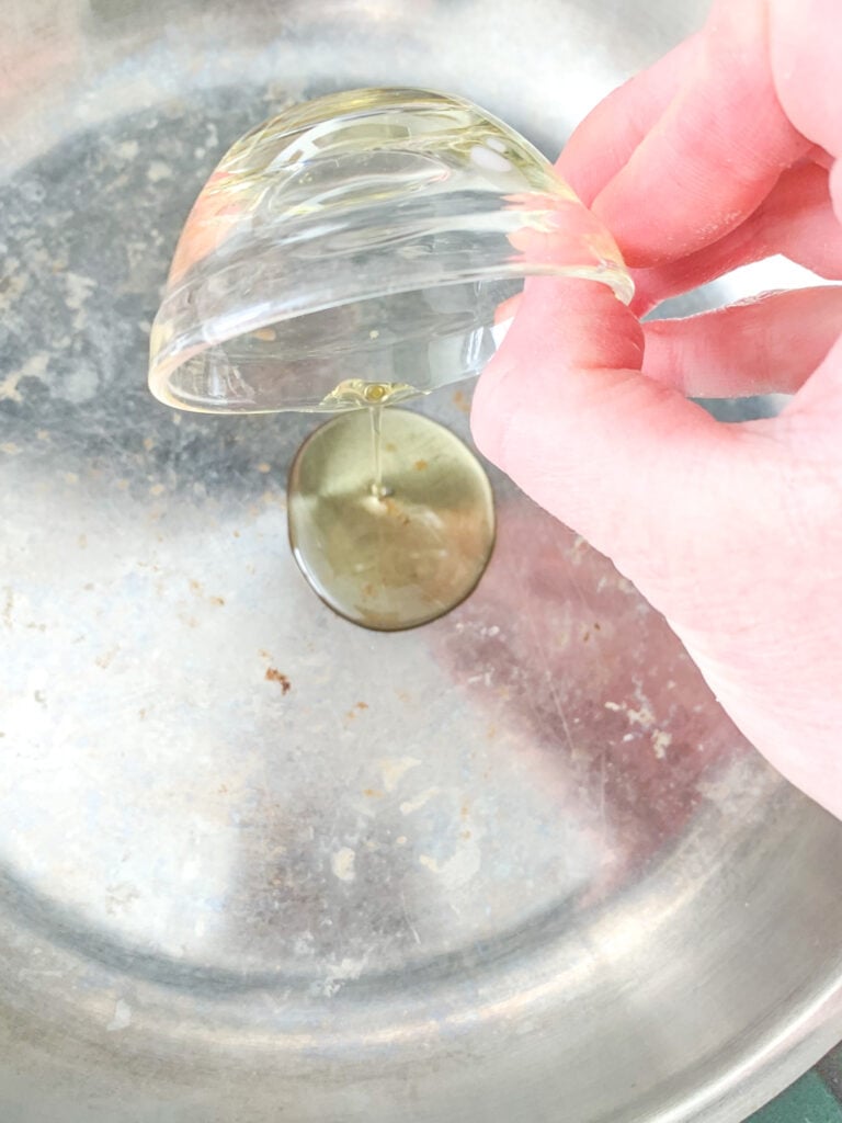 adding avocado oil to skillet before searing chicken