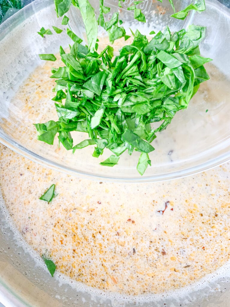 adding spinach to tuscan sauce