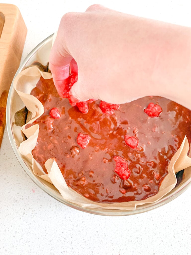 adding raspberries to the top of brownie batter