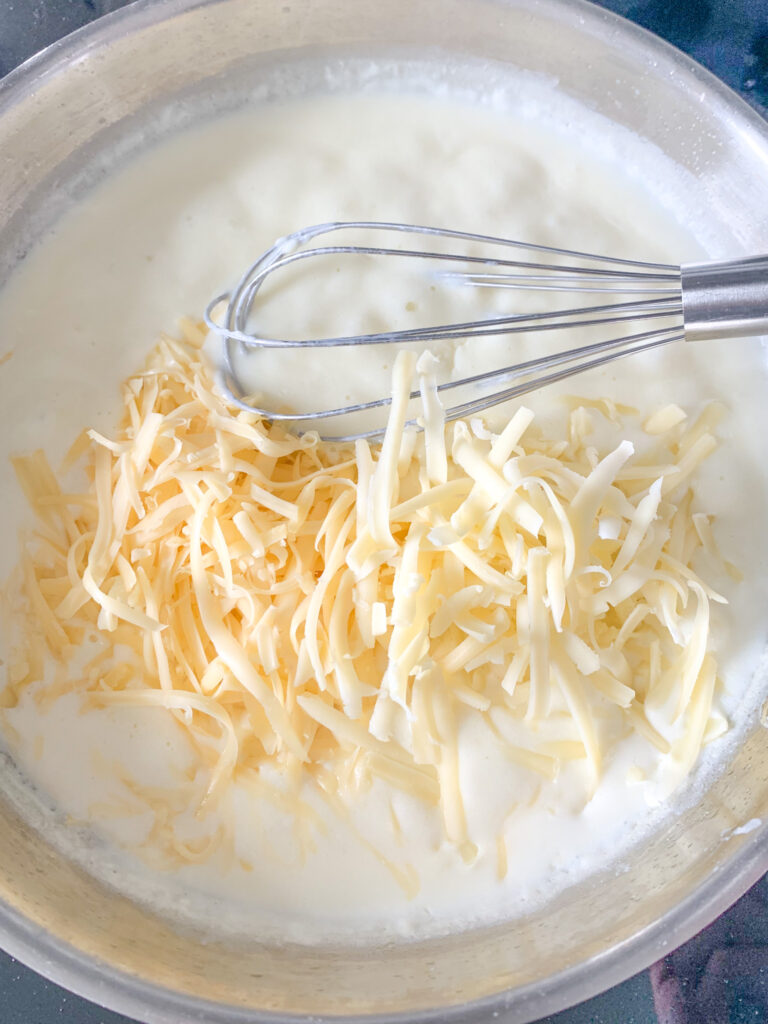 whisking in shredded cheeses for mac and cheese sauce