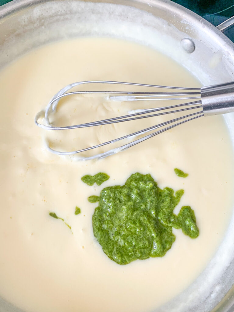whisking pesto into mac and cheese sauce