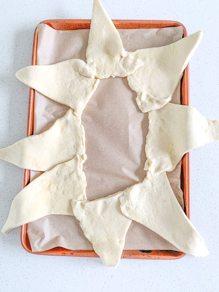 sourdough crescent dough triangles lined in an oval on sheet pan