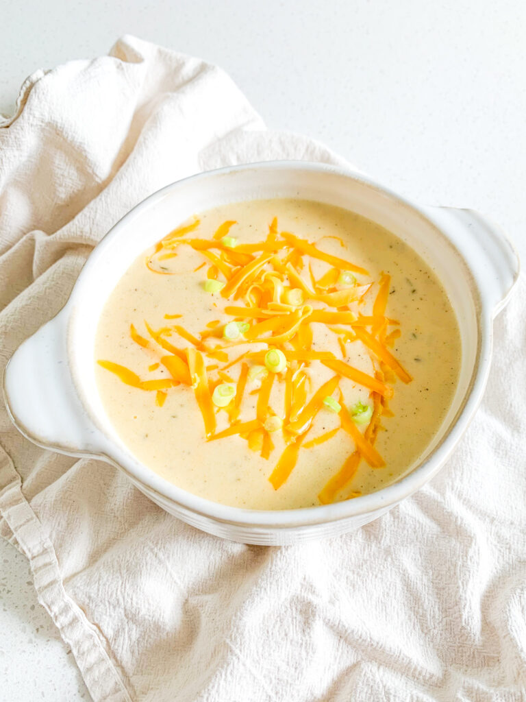 freshly cooked cheesy potato soup in a bowl with shredded cheese and green onions on top