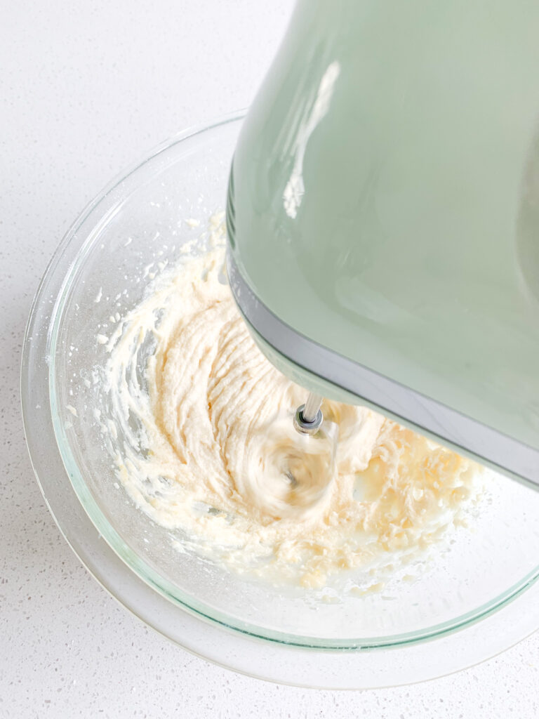 lemon buttercream frosting getting mixed in a bowl with a hand mixer