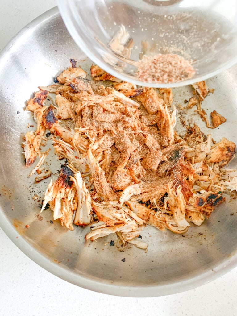 shredded chicken getting tossed in extra seasoning