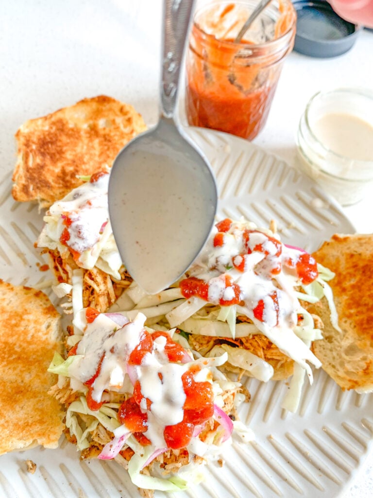 adding white bbq sauce to sliders