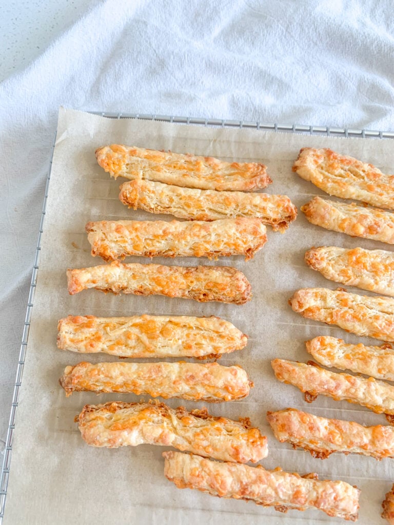 freshly baked cheese straws cooling on a rack