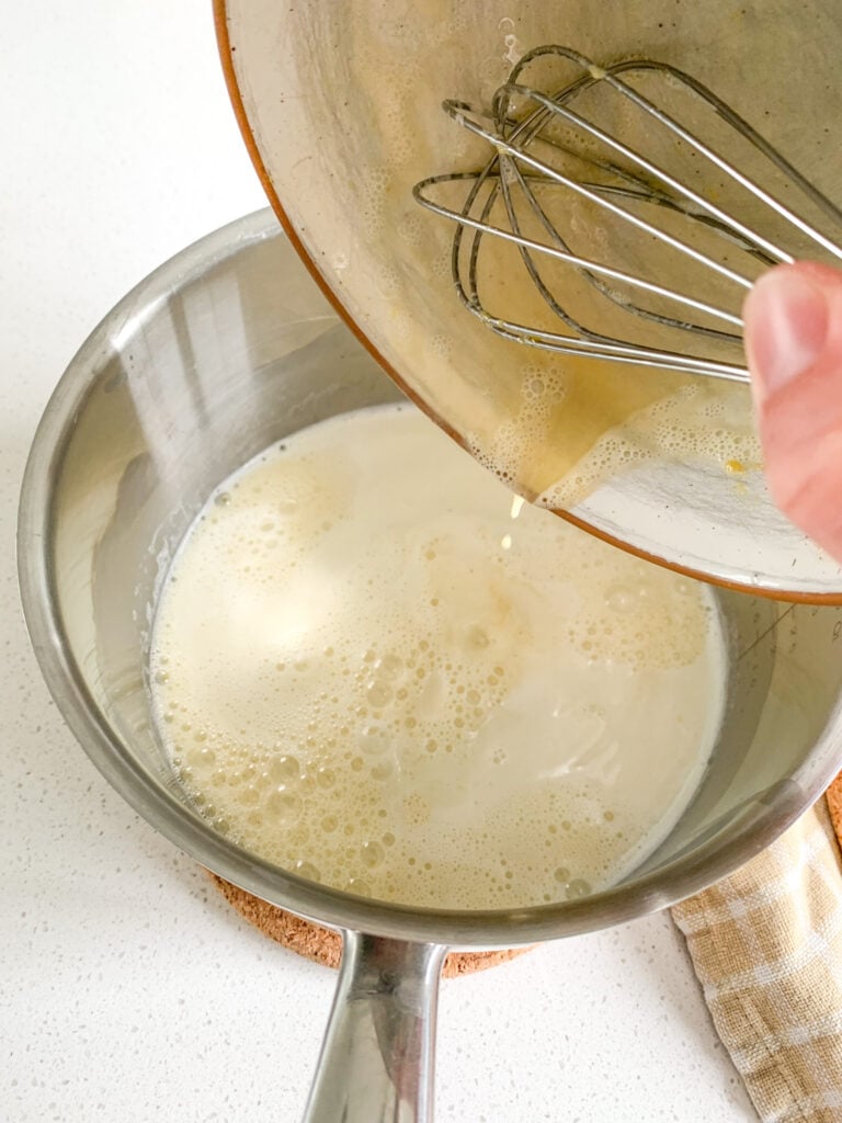 adding tempered eggs to milk to make pudding