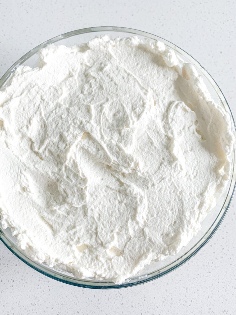 homemade whipped cream spread on top of banana pudding