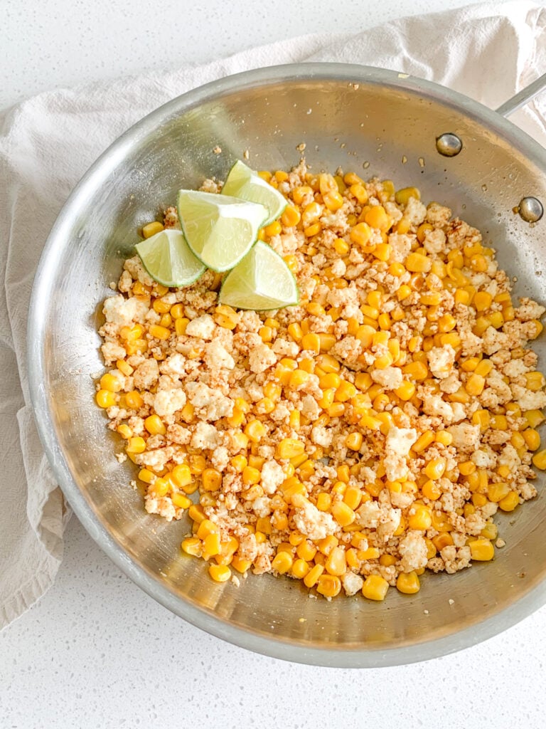 freshly cooked mexican street corn salad with a fresh lime on the side