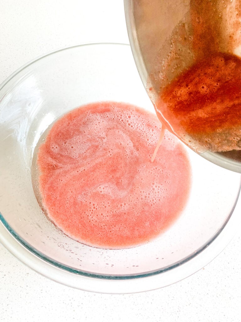 pouring hot strawberry mixture bowl with gelatin water