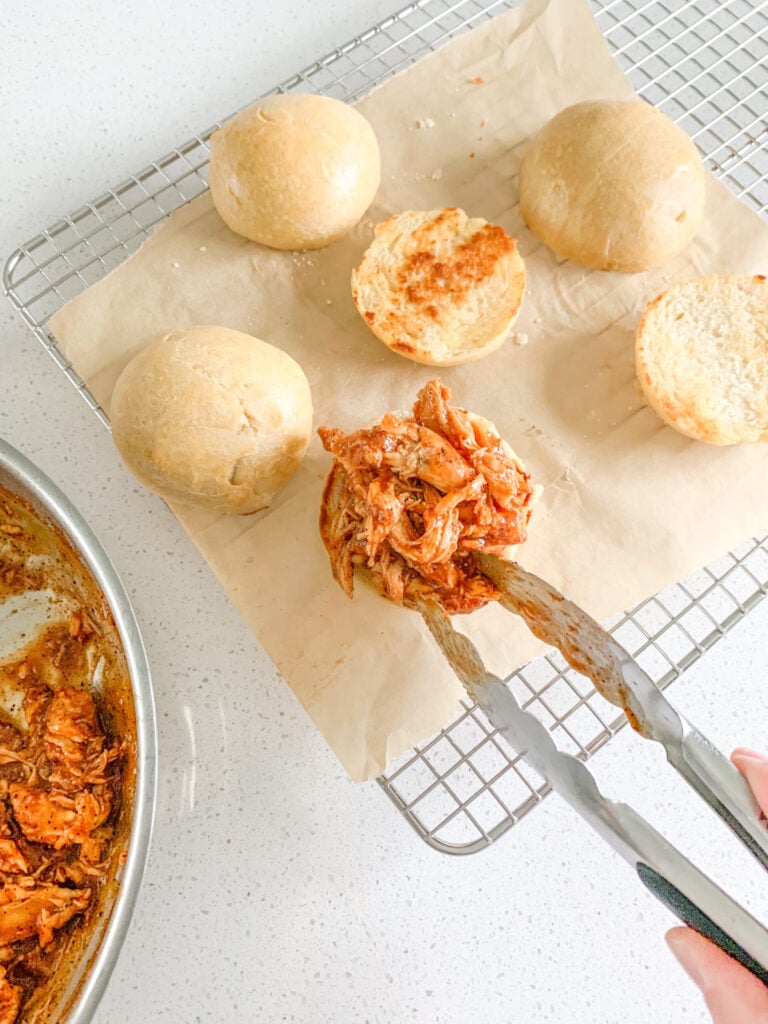 adding shredded bbq chicken to buns